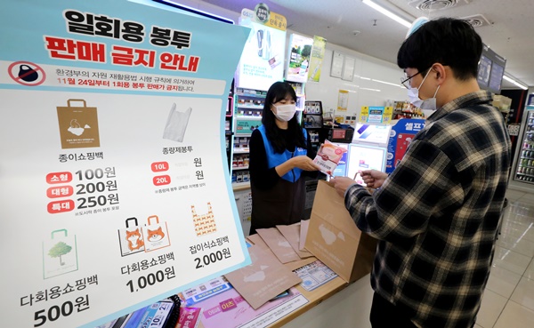 서울 강남구에 위치한 GS25 편의점에서 직원이 일회용 비닐봉투를 대신해 종이쇼핑백에 물건을 담아주고 있다. [사진=뉴스1]