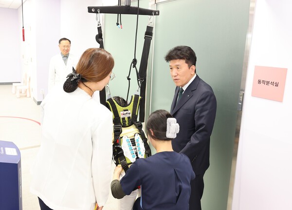함영주 회장(사진 맨 오른쪽)이 워킹레일 보행치료를 받고 있는 장애 아동에게 따뜻한 격려의 말을 전하고 있다. [사진=하나금융그룹]